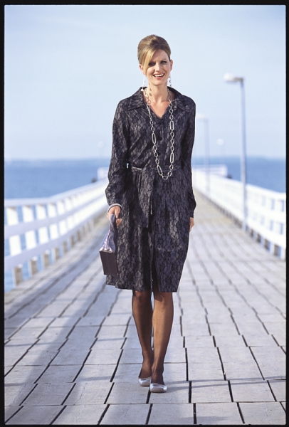 Modisches Kleid mit dunklem, abstraktem Muster, gerader Schnitt. Kette als Hingucker, stilvolle Mode.