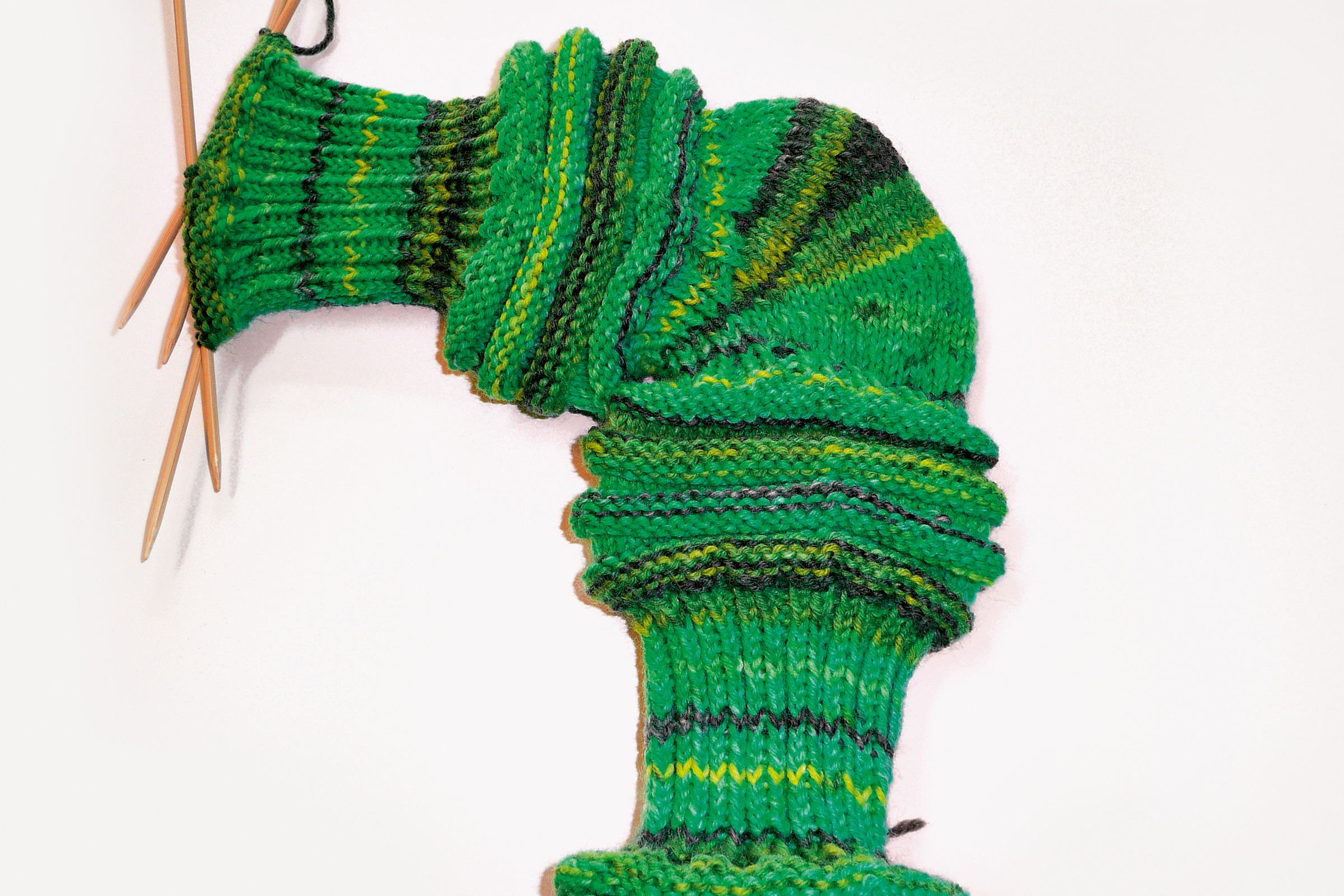 Grüner gestrickter Socken, vielfarbig, handgemacht, DIY-Style, mit Nadeln fixiert. Modisches Accessoire.