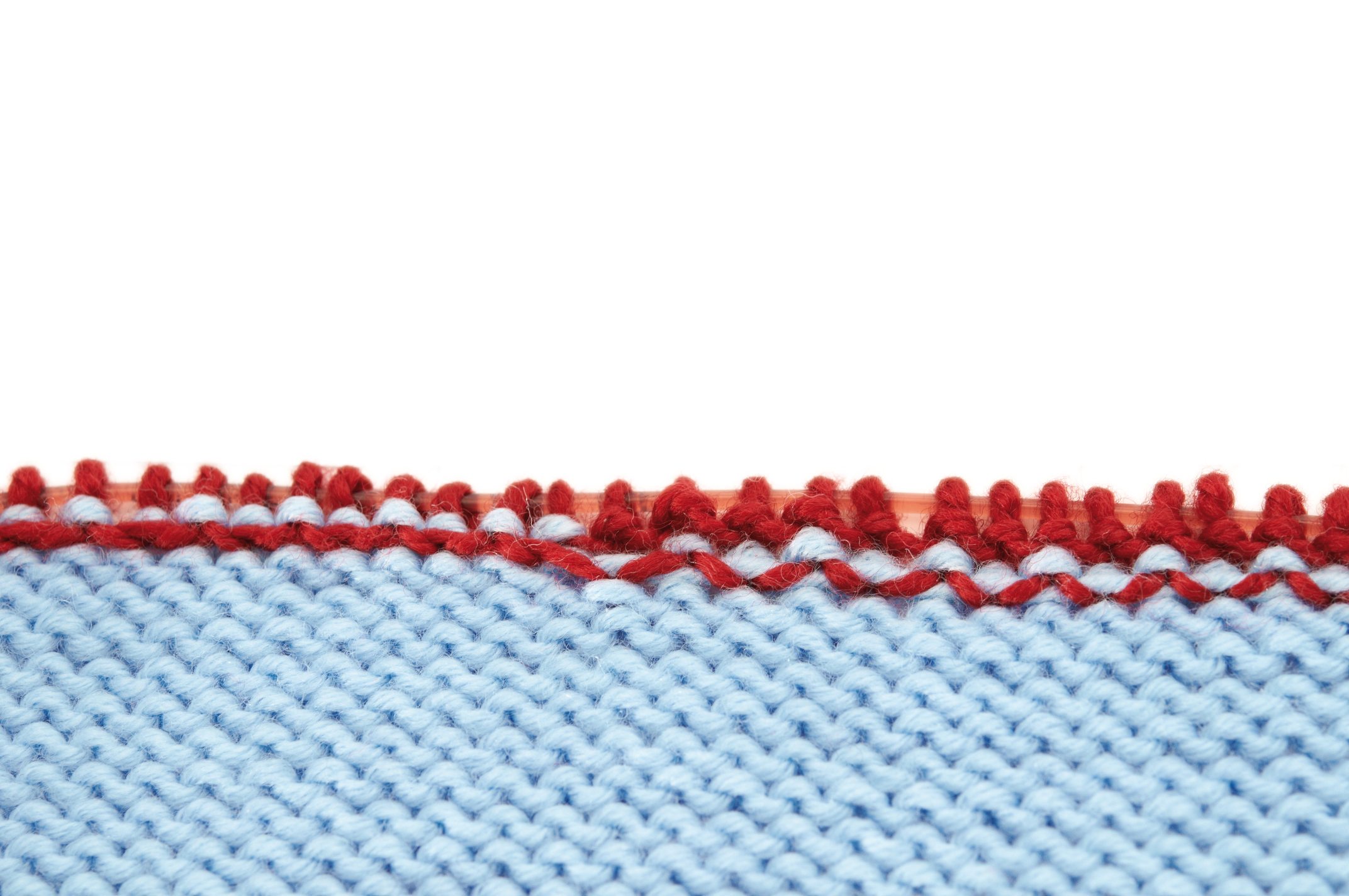 Hellblaues, gestricktes Muster mit roter Zierkante. Handarbeit, DIY, modisch und kreativ gestaltet.