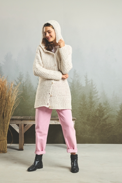 Modischer, handgemachter Strickmantel in Creme; kombiniert mit pastellrosa Hose, schwarze Stiefeletten, DIY-Charme.