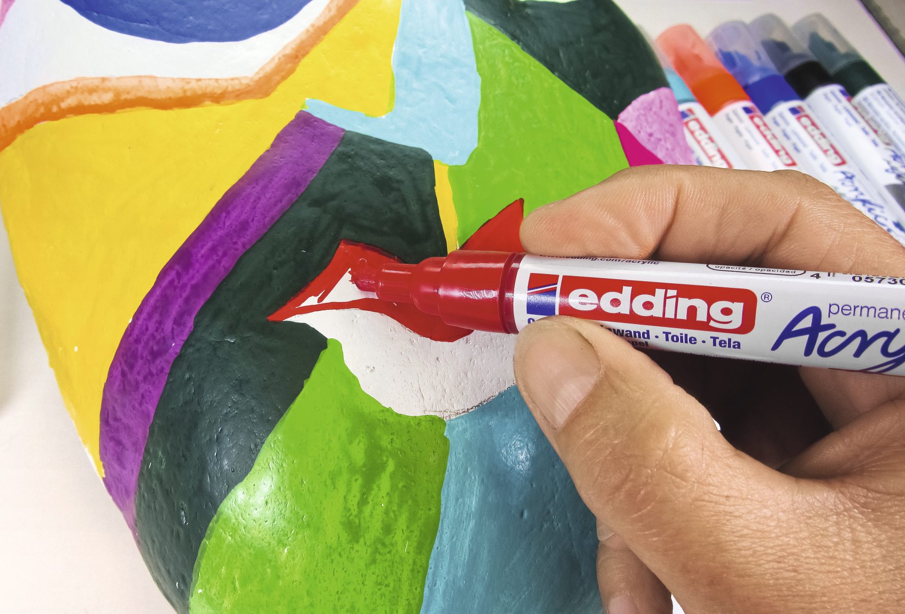 Bunt gemusterte, handgemachte Maske mit markanten Farben und kreativen Formen, bemalt mit Acrylmarker.