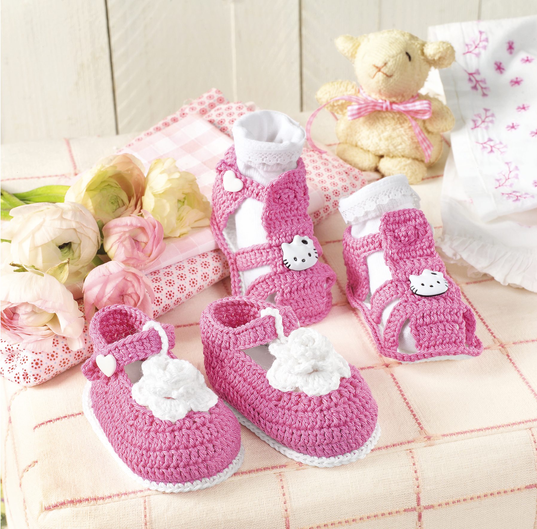 Rosa handgearbeitete Babyschuhe, gehäkelt, mit weißen Blumen und Herz-Details, modisch und einzigartig.