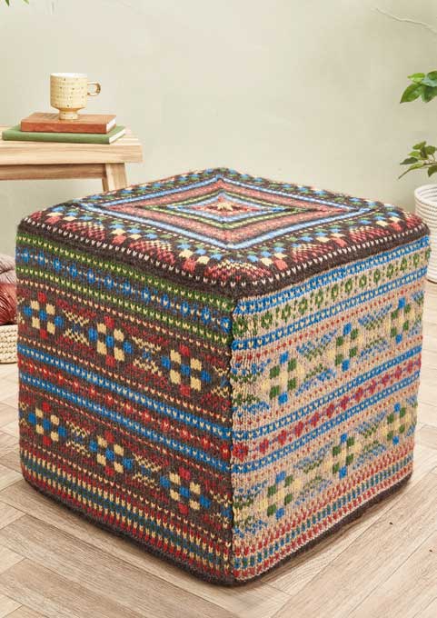 Handgefertigter Pouf mit farbenfrohem Fair-Isle-Muster, lebhaften Tönen und geometrischen Designs. Strick, farbenprächtig.