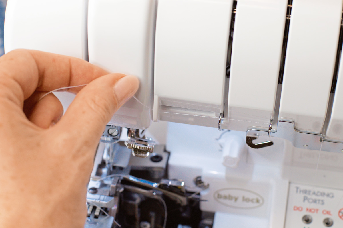 Hand hält weißen Faden, moderne Maschine, präzise Mechanik, DIY-Hobby, Näharbeit.