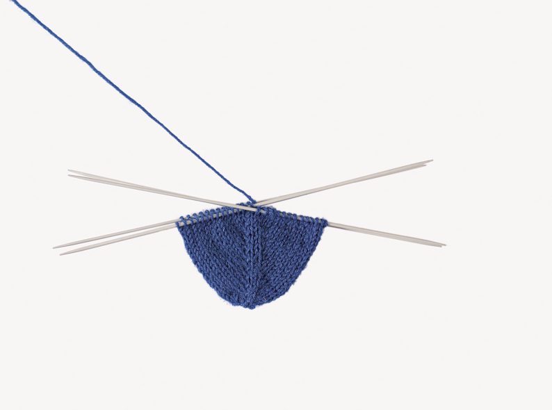 Blaues Handstrickprojekt, vier Nadeln, dreieckiger Schnitt, modisch, DIY, Handarbeit.
