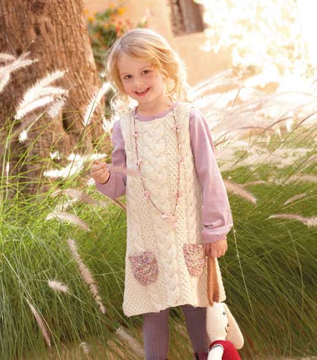Modisches Strickkleid in Creme mit Zopfmuster, fliederfarbenen Akzenten und handgefertigten Taschen, DIY-Look.