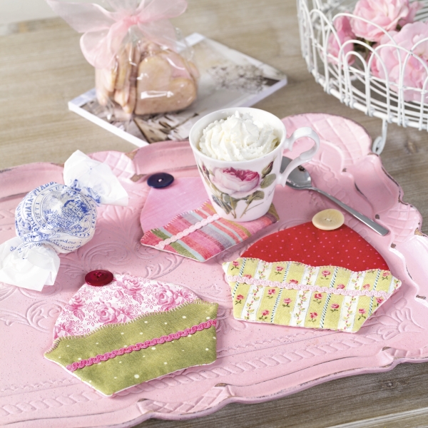 Handgemachte Untersetzer in Cupcake-Form, bunt gemustert mit Knopfverzierungen. Modische, kreative Gestaltung.