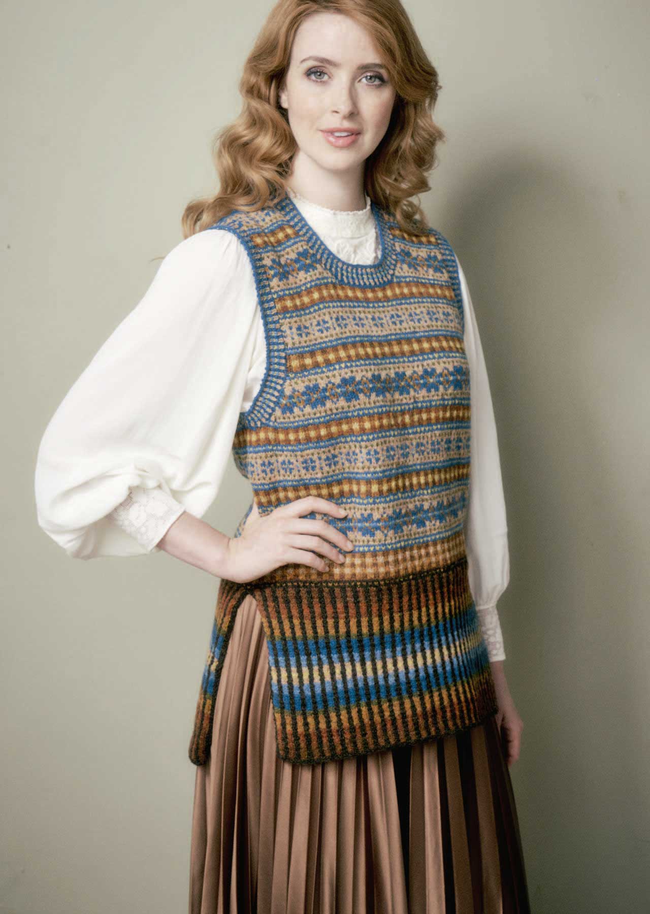 Bunte, gestrickte Weste mit geometrischem Muster, kombiniert mit weißer Bluse. Modisch, handgemacht.