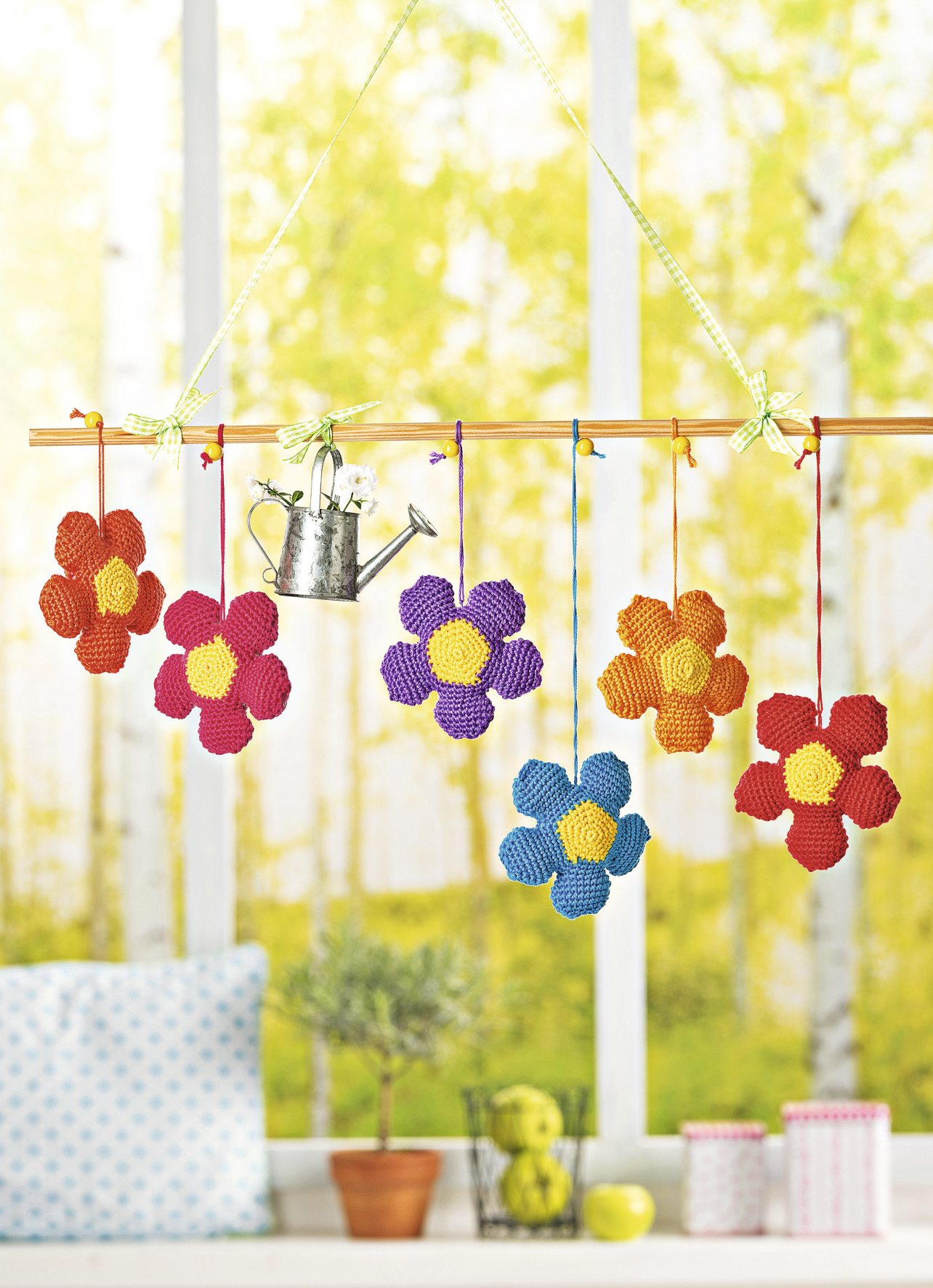 Farbenfrohe, handgemachte Häkelblumen in Rot, Lila, Blau und Orange als fröhliche DIY-Deko aufgereiht.