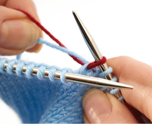 Modisches, handgemachtes Strickmuster in Blau mit roten Akzenten. Elegante Handarbeit, DIY.