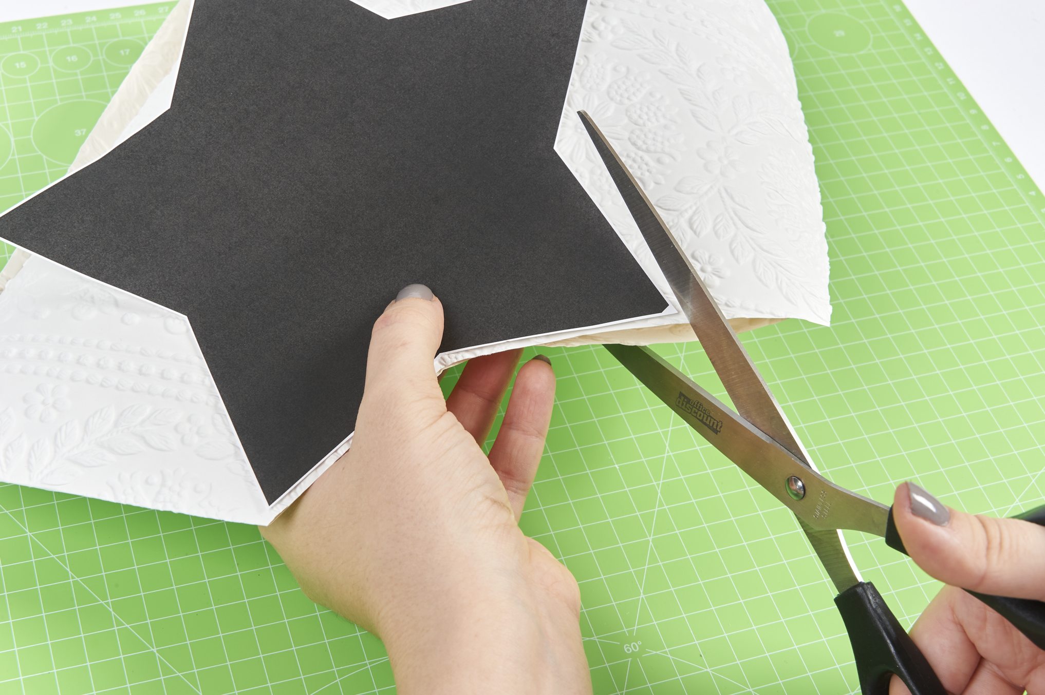 Hand schneidet schwarzen Papierstern; DIY, handgemacht, kreativ, modisch, selbstgemacht.