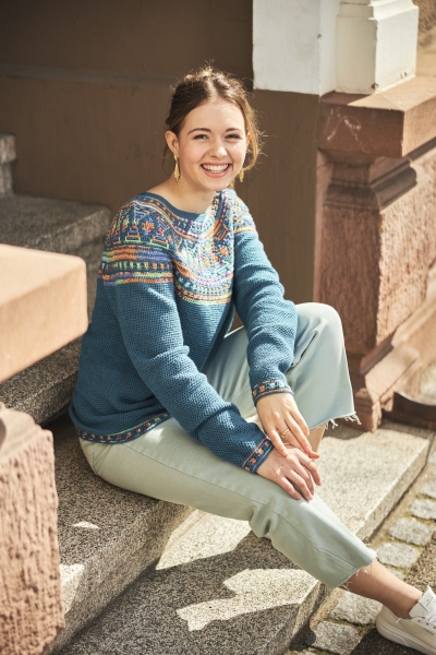 Blauer Strickpullover mit buntem, nordischem Muster; pastellgrüne Hose. Modisch, handgemacht.