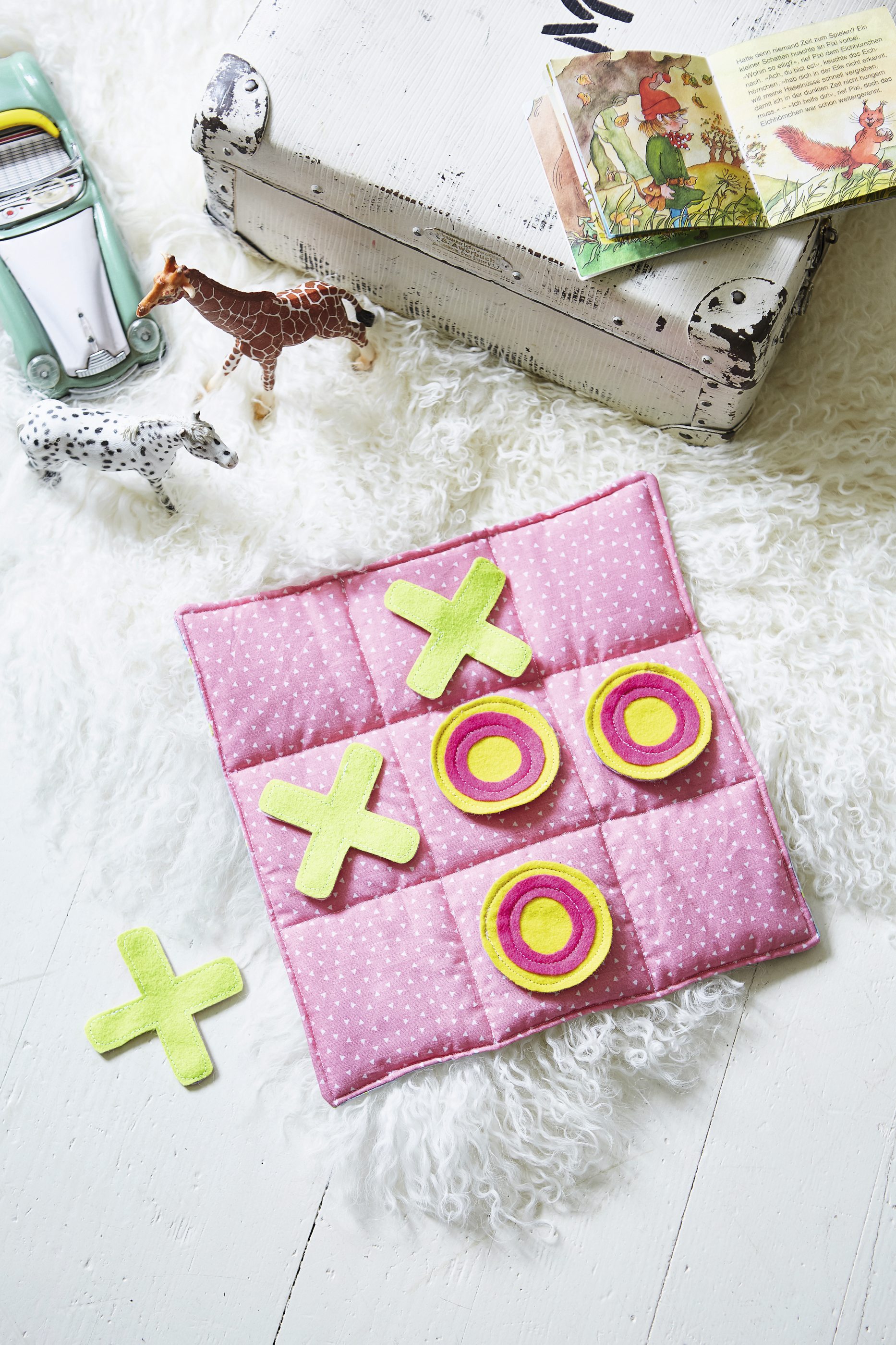 Ein modisches, DIY Tic-Tac-Toe aus rosa gepunktetem Stoff mit X- und O-Pieces in Grün und Gelb.
