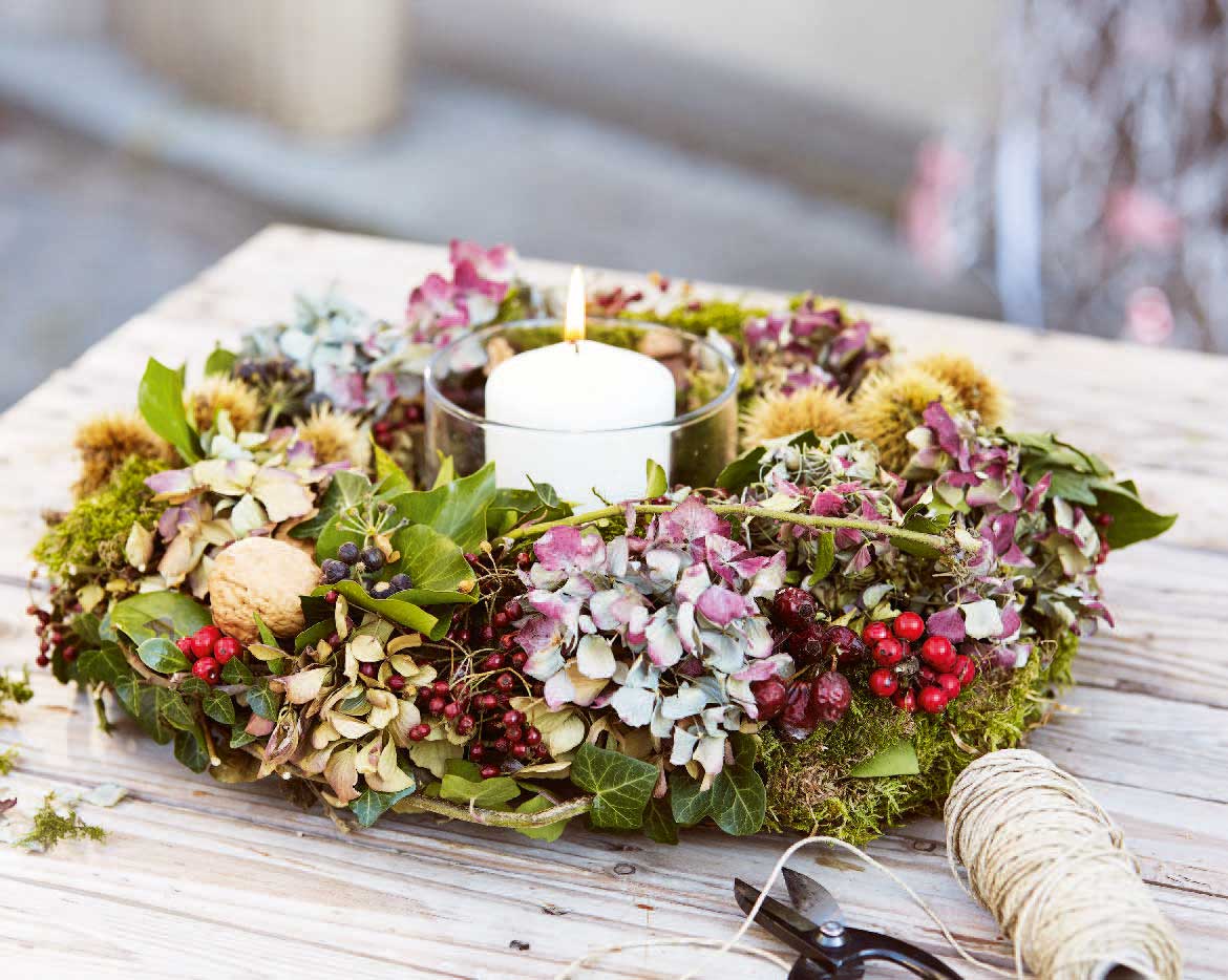 Bunter selbstgemachter Kranz mit Blüten, Beeren und Moos; handgemacht, herbstlich, dekorativ.