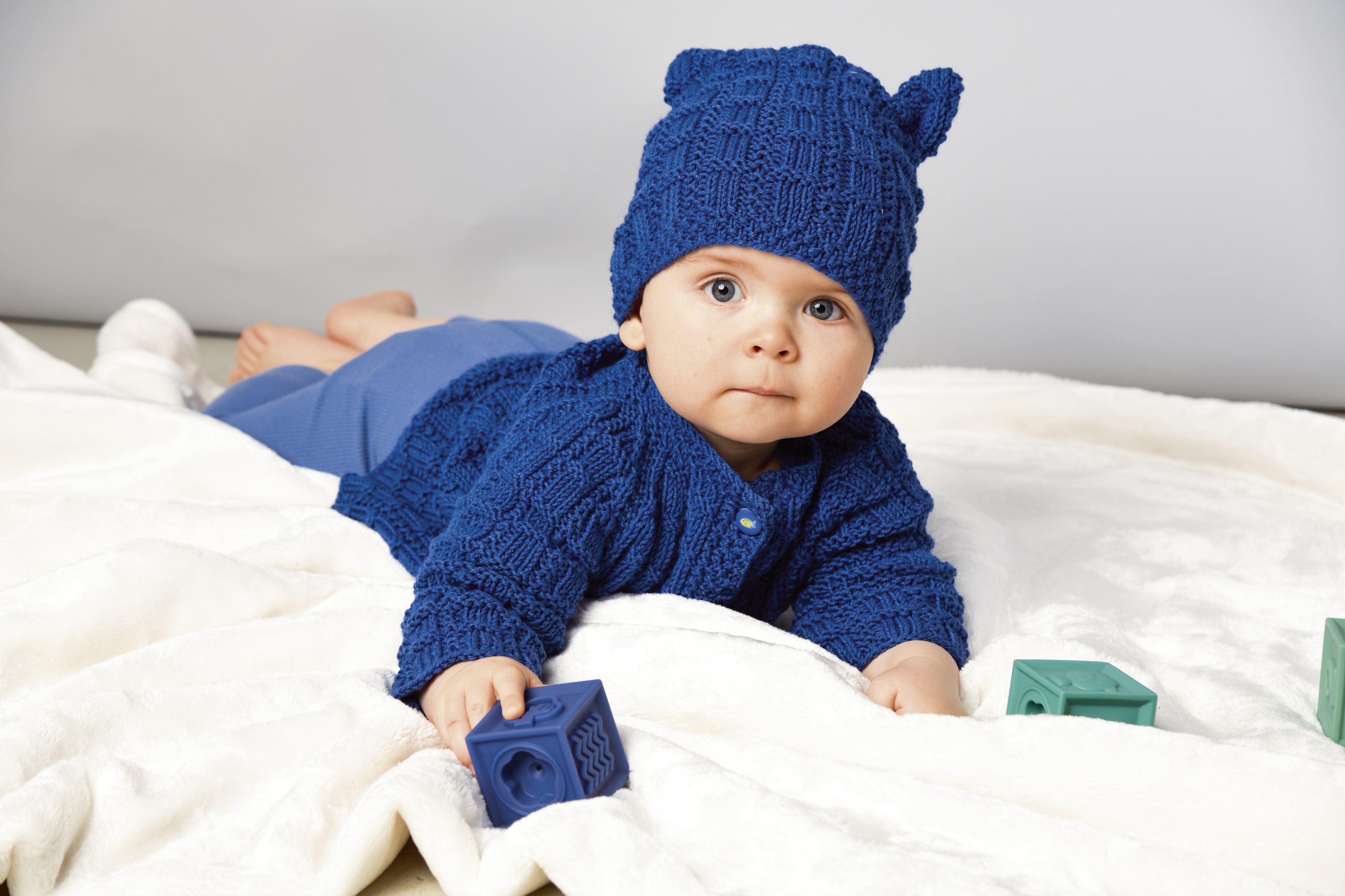 Stylisches, handgestricktes Set in Blau mit Ohrenmütze. Weiche Textur, modisches Muster, perfekter Babylook.