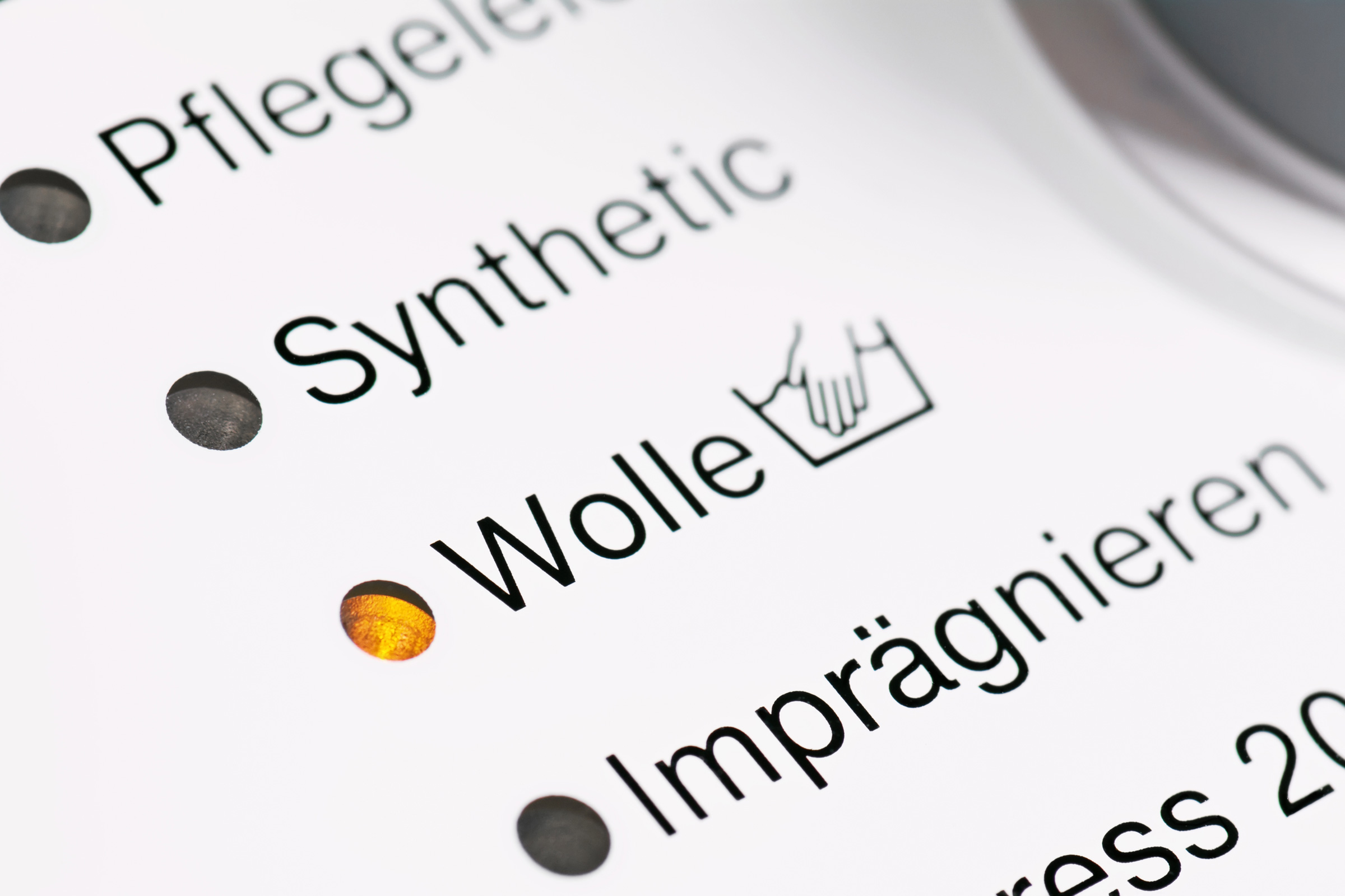 Nahaufnahme von Pflegeprogrammen auf einer Maschine mit Fokus auf Wolle. Minimalistisch, klar, praktisch.