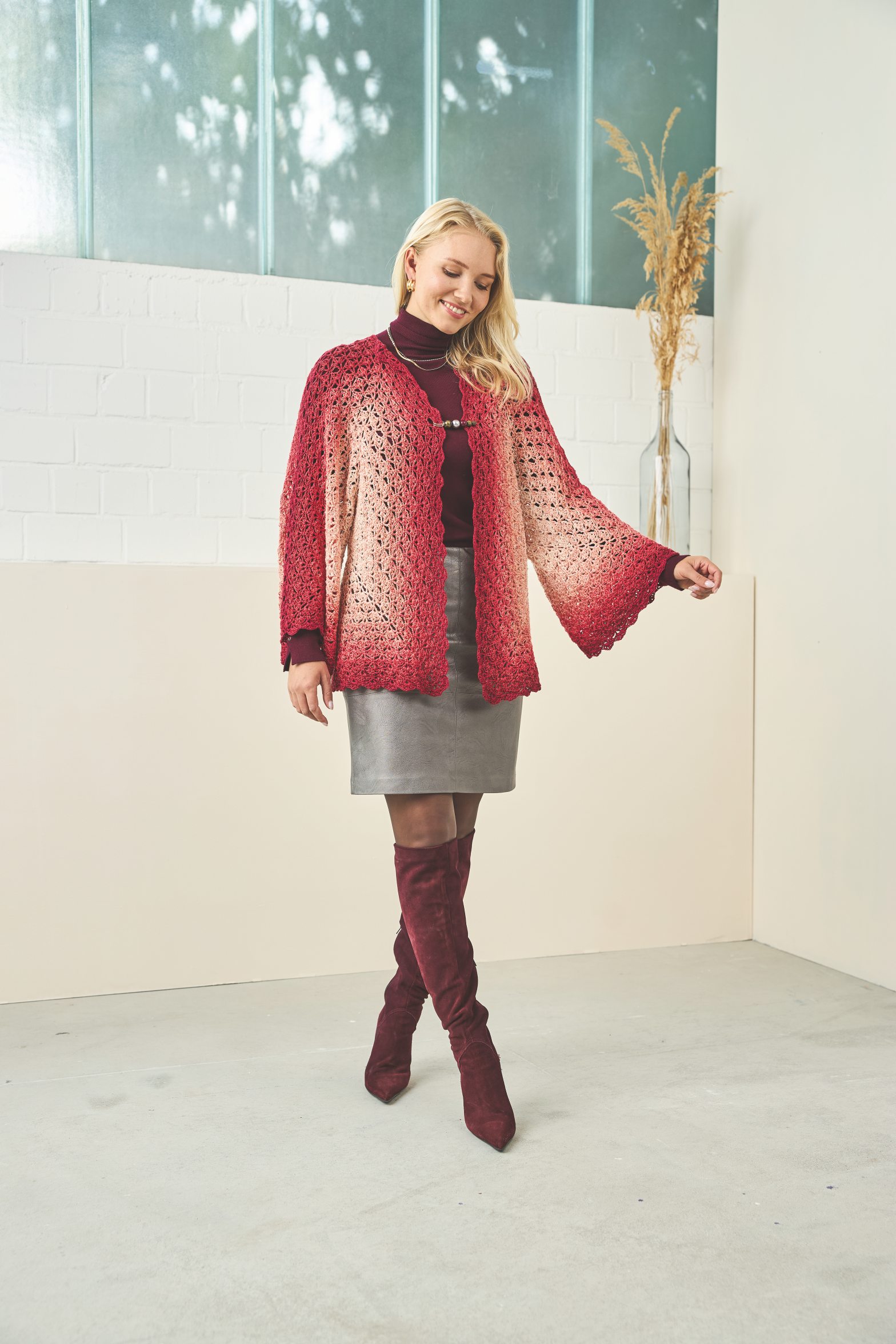 Modische rote Strickjacke mit Ombre-Muster, grauer Rock, passende Overknee-Stiefel. Stilvoll und handgefertigt.