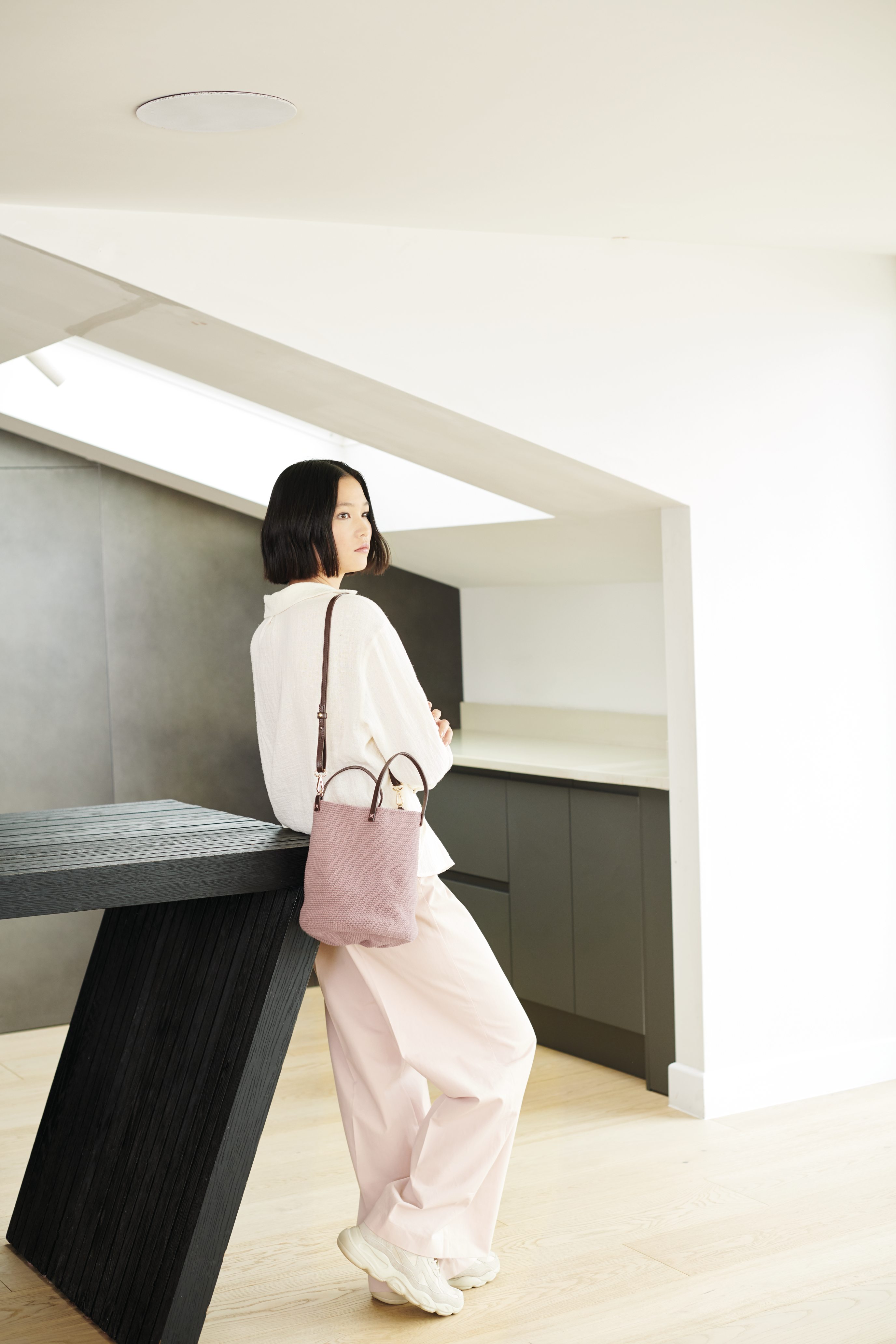 Weiße, lockere Bluse, rosafarbene Hose, modische rosa Tasche; schlicht, elegant, minimalistisch.