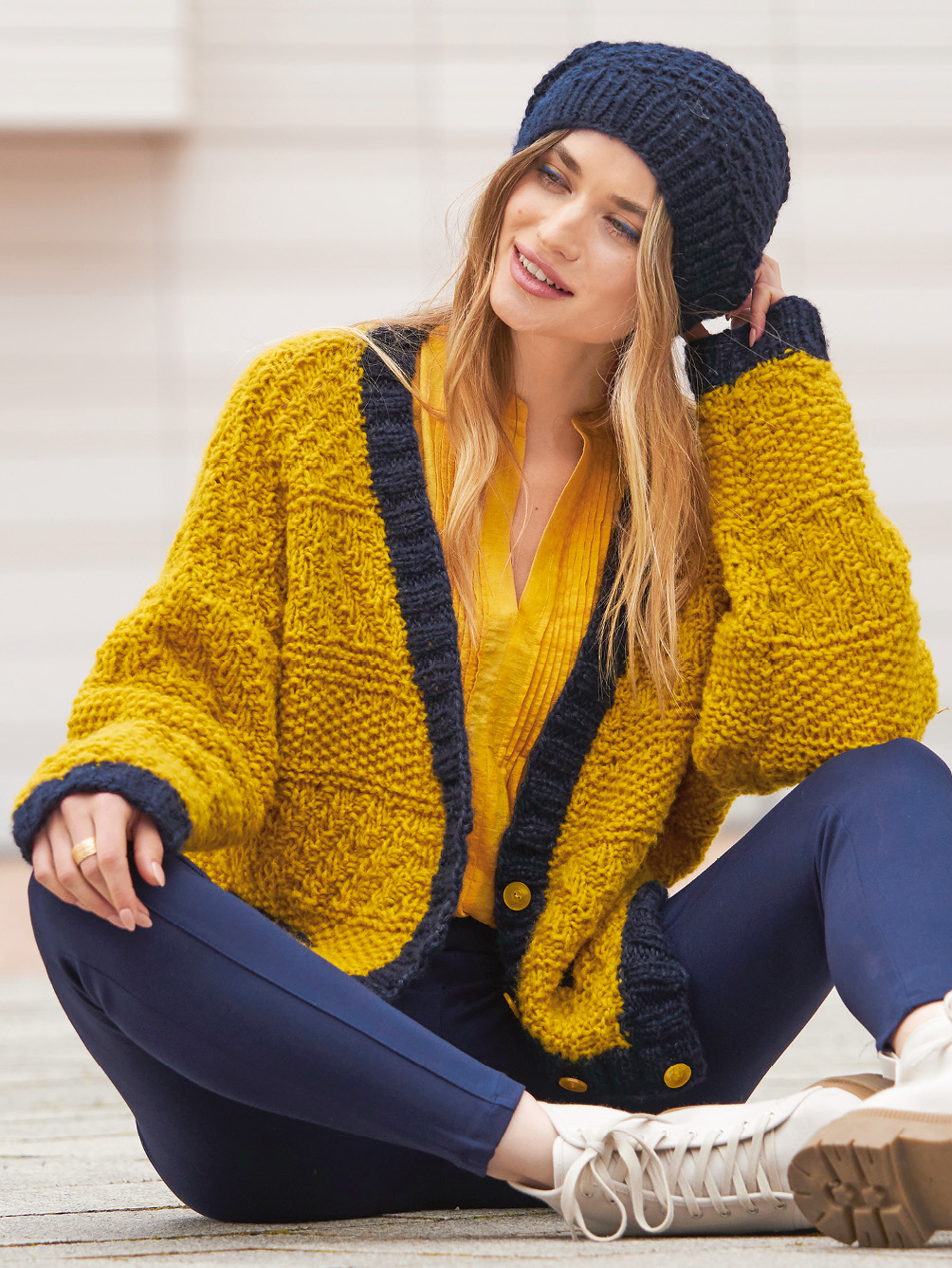 Modellansicht Bild 1: Jacke in Gelb und Marineblau plus Mütze in Marineblau und Mütze in Marineblau