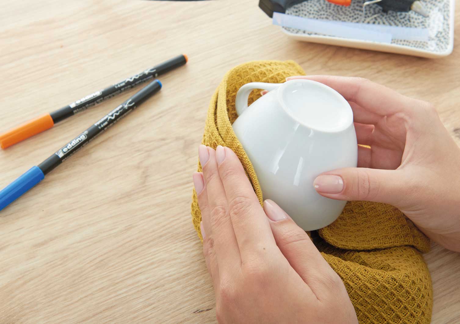 Gelbes, handgemachtes Geschirrtuch in Waffelmuster, um eine weiße Tasse gewickelt. Modisch und funktional.