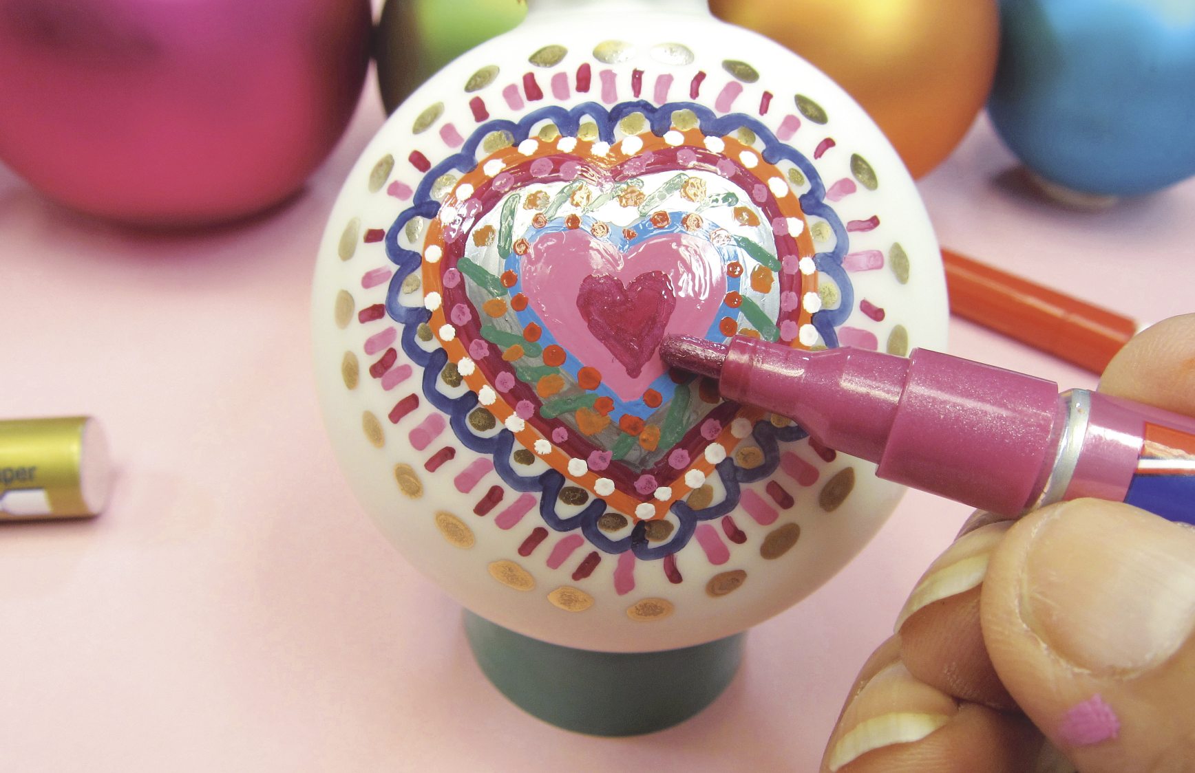 Herzornament, handgemalt; bunte Muster, DIY-Stil, lebhafte Farben mit Gold- und Pinktönen.