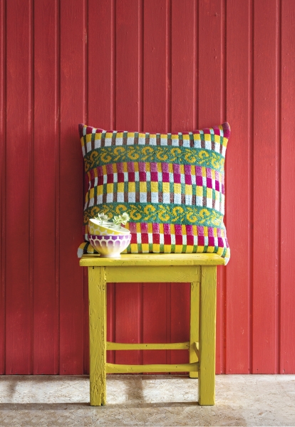 Gestreiftes, handgemachtes Kissen in lebendigen Farben auf gelbem Stuhl. Modisch, kreativ, DIY-Design.