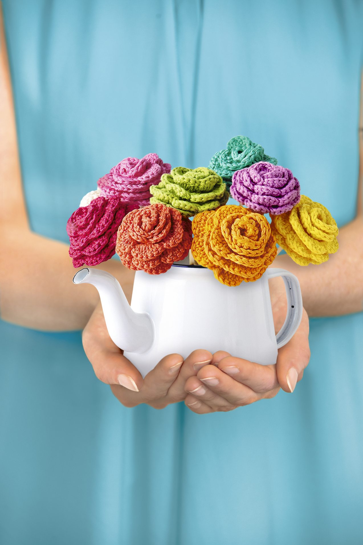 Kreative, handgemachte Blumen aus bunter Wolle in Teekanne. Farbenfroh, DIY, stilvoll, detailreich.