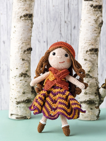 Handgemachte Puppe mit bunter, gestreifter Häkelkleidung, elegantem Muster, modisch mit Mütze und Schal.