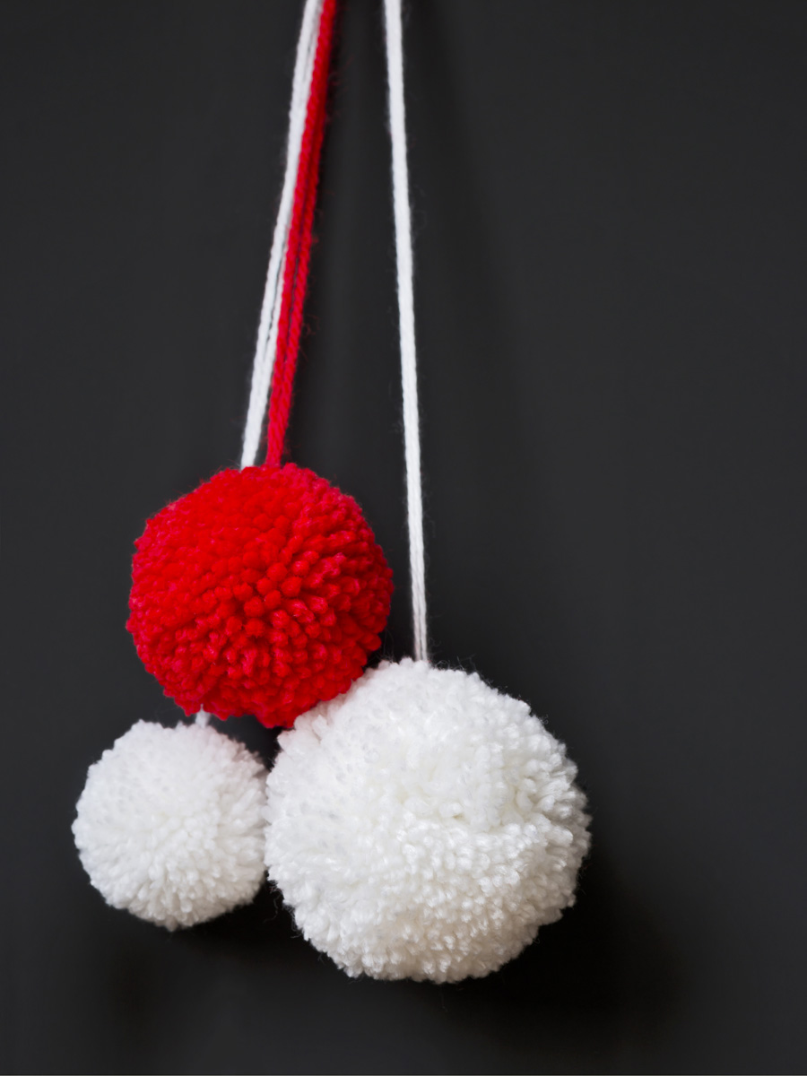 Rote und weiße, selbstgemachte Pompons; flauschig, kontrastreich. Modische DIY-Deko-Kunst.