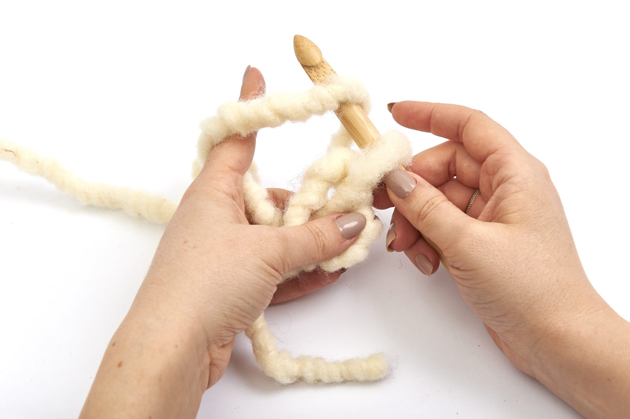 Handgemachte Häkelarbeit. Dicke, cremefarbene Wolle. DIY, Handarbeit, kreative Technik.