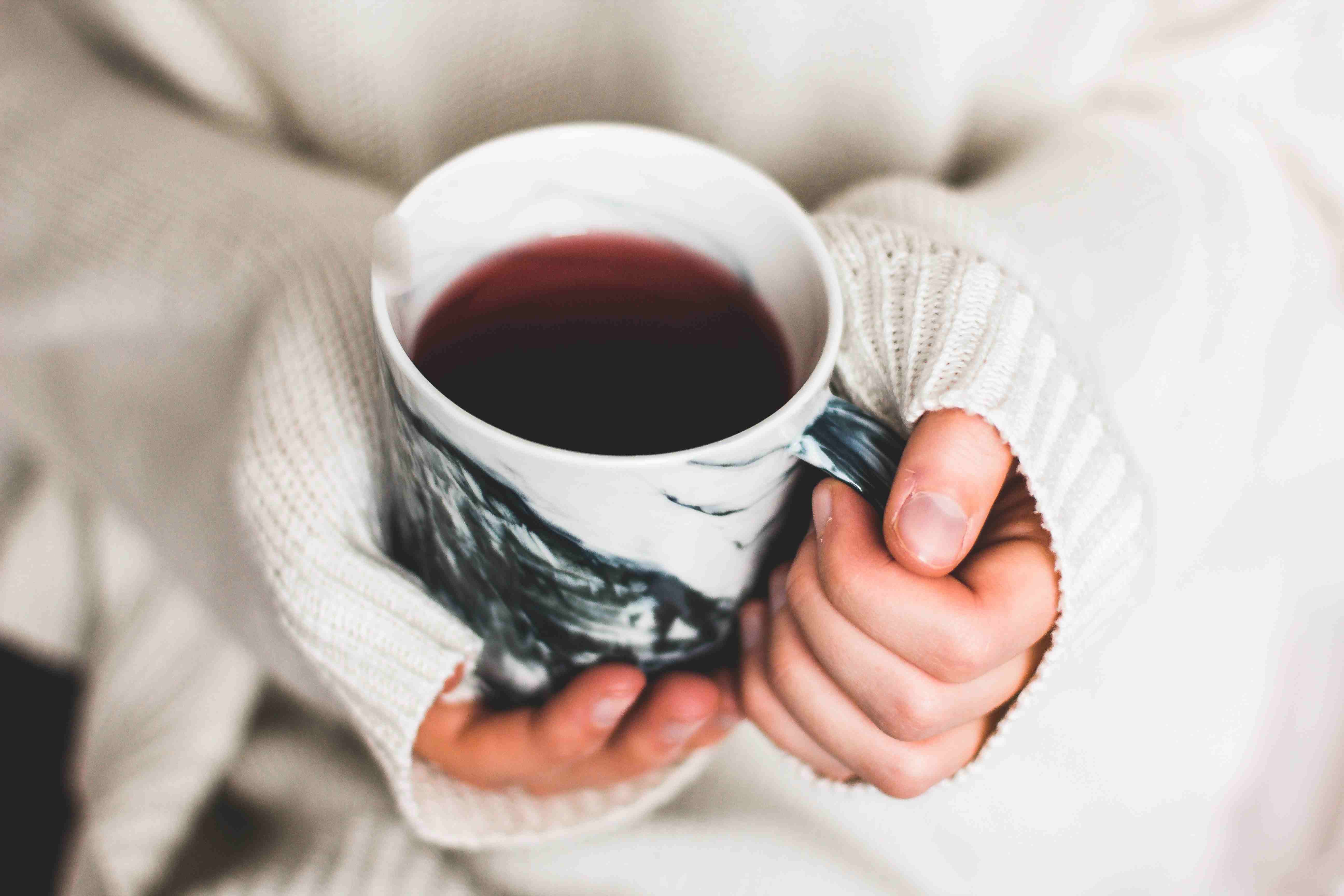 Strukturierter, weißer Strickpulli mit langen Ärmeln. Marmortasse. Handarbeit, gemütlich, stilvoll.