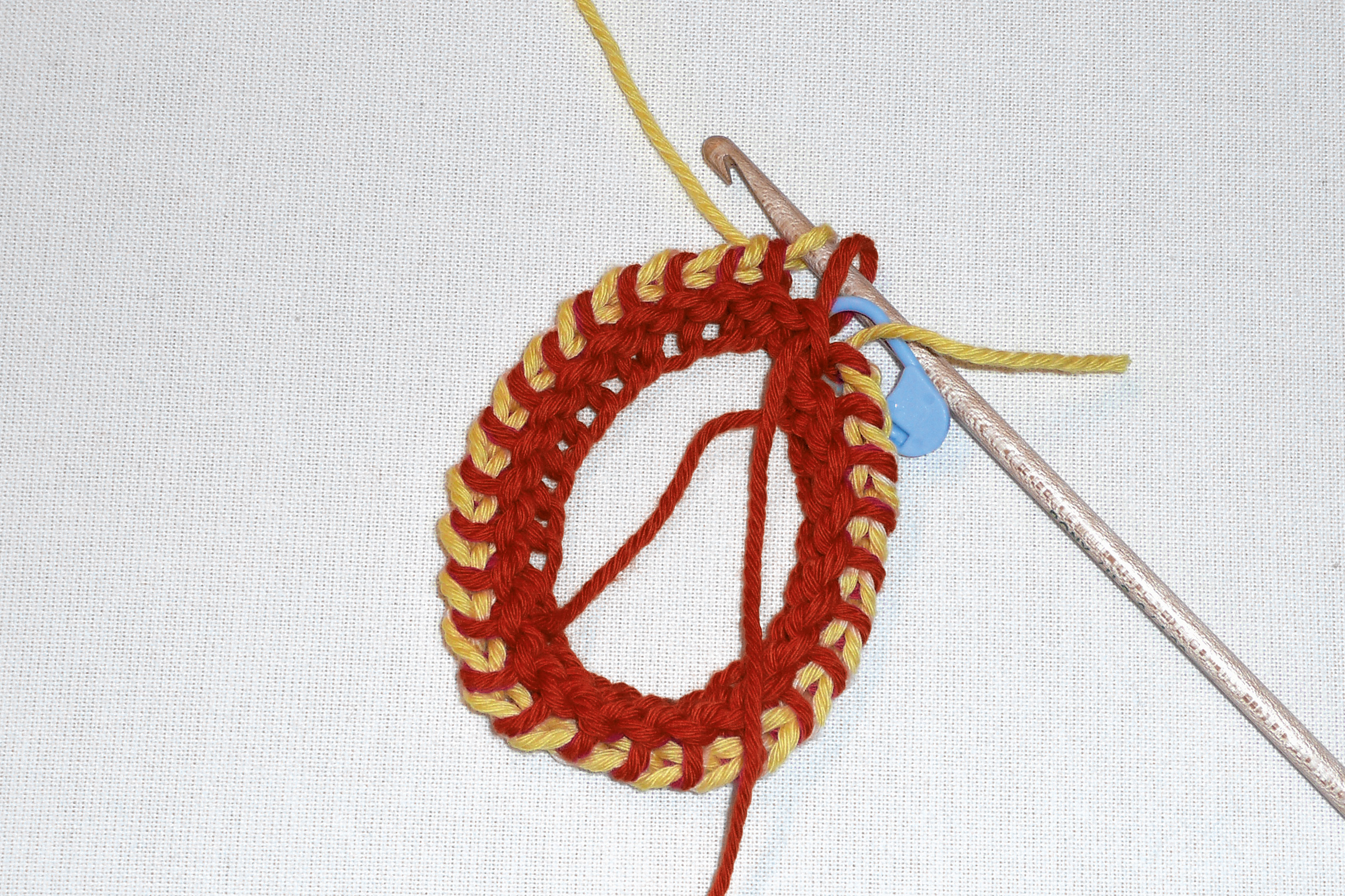 Rot-gelbes, handgemachtes Häkelstück mit markantem Muster, DIY-Charme, innovativer Schnitt.