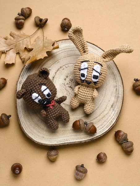 Zwei gehäkelte Tiere, braun und beige, mit großen Augen und feinen Details. Modisch, DIY, individuell gestaltet.