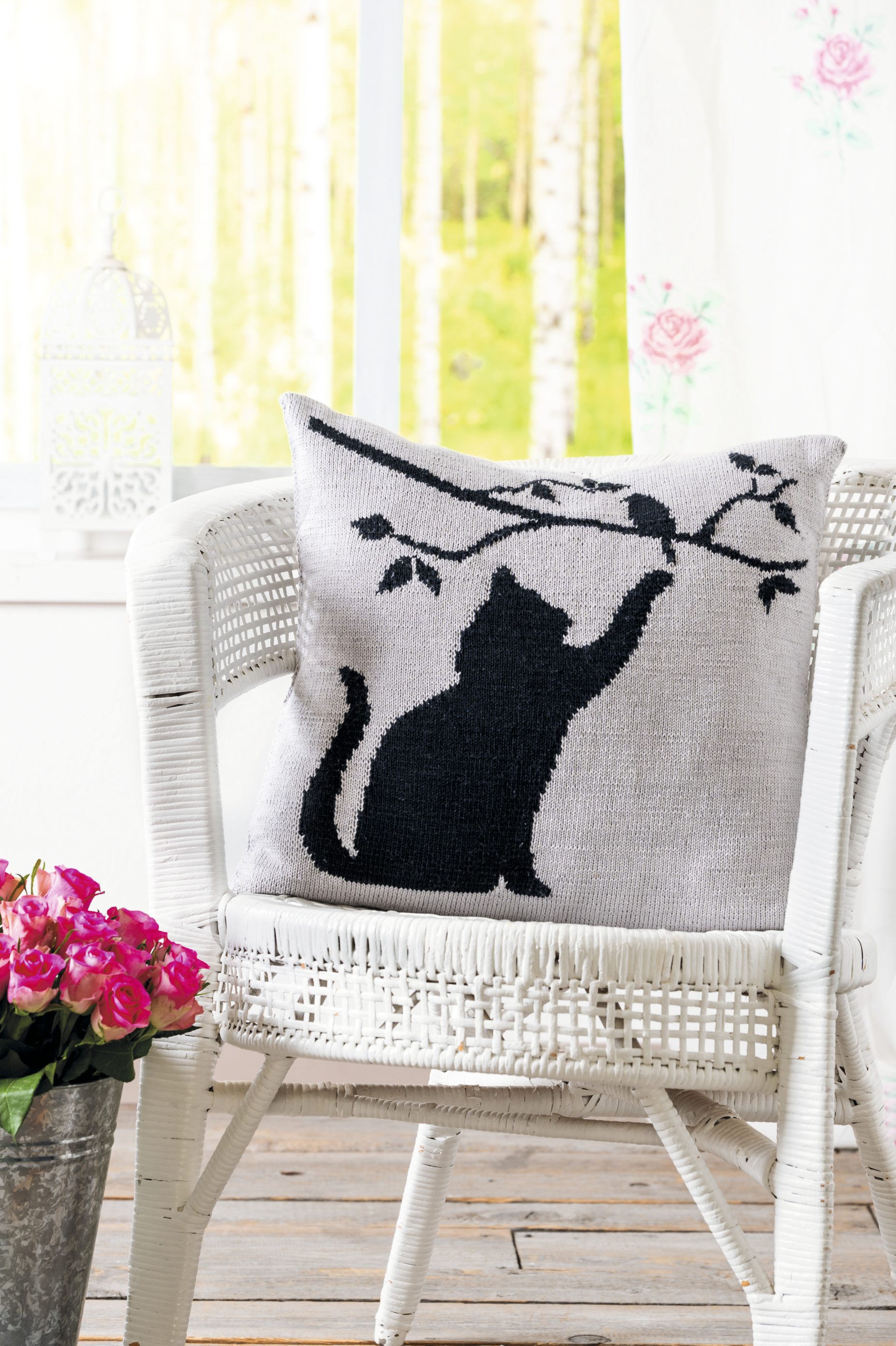 Gestricktes Kissen mit schwarzem Katzenmotiv auf hellgrauem Hintergrund. Stylisch, handgearbeitet, einzigartig.