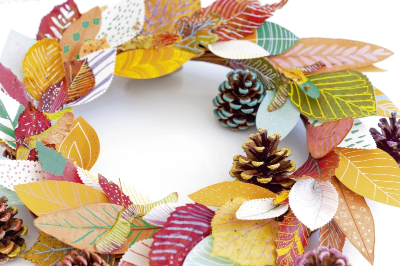 Bunter Kranz aus Papierblättern und Zapfen. Modisch handgemacht, mit vielfältigen Mustern und warmen Herbstfarben.