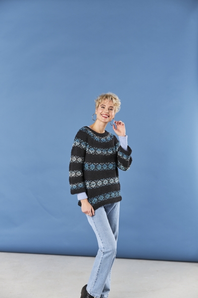 Modischer Strickpullover mit blauen Mustern, kombiniert mit hellblauen Jeans. Besonders: handgefertigtes Design.