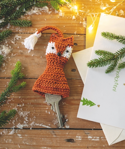 Selbstgemachter, gestrickter Fuchs-Schlüsselüberzug in warmem Orange und Weiß; modischer DIY-Begleiter.