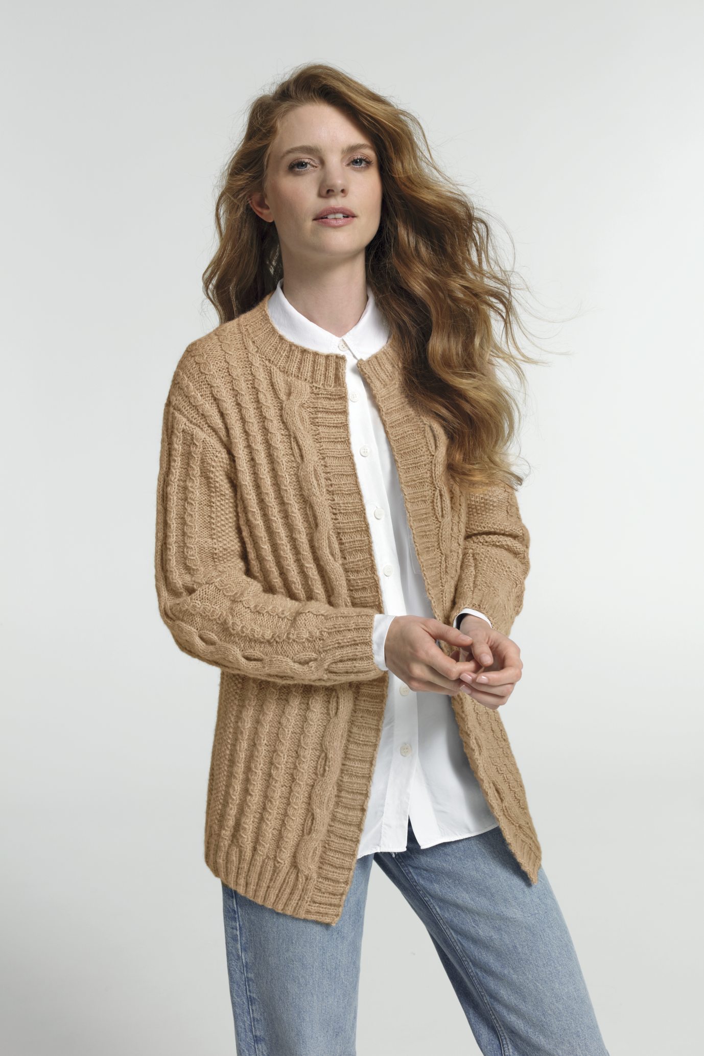 Beiger, grob gestrickter Cardigan, modisch, handarbeit, lockerer Schnitt, über weißem Hemd und blauer Jeans.