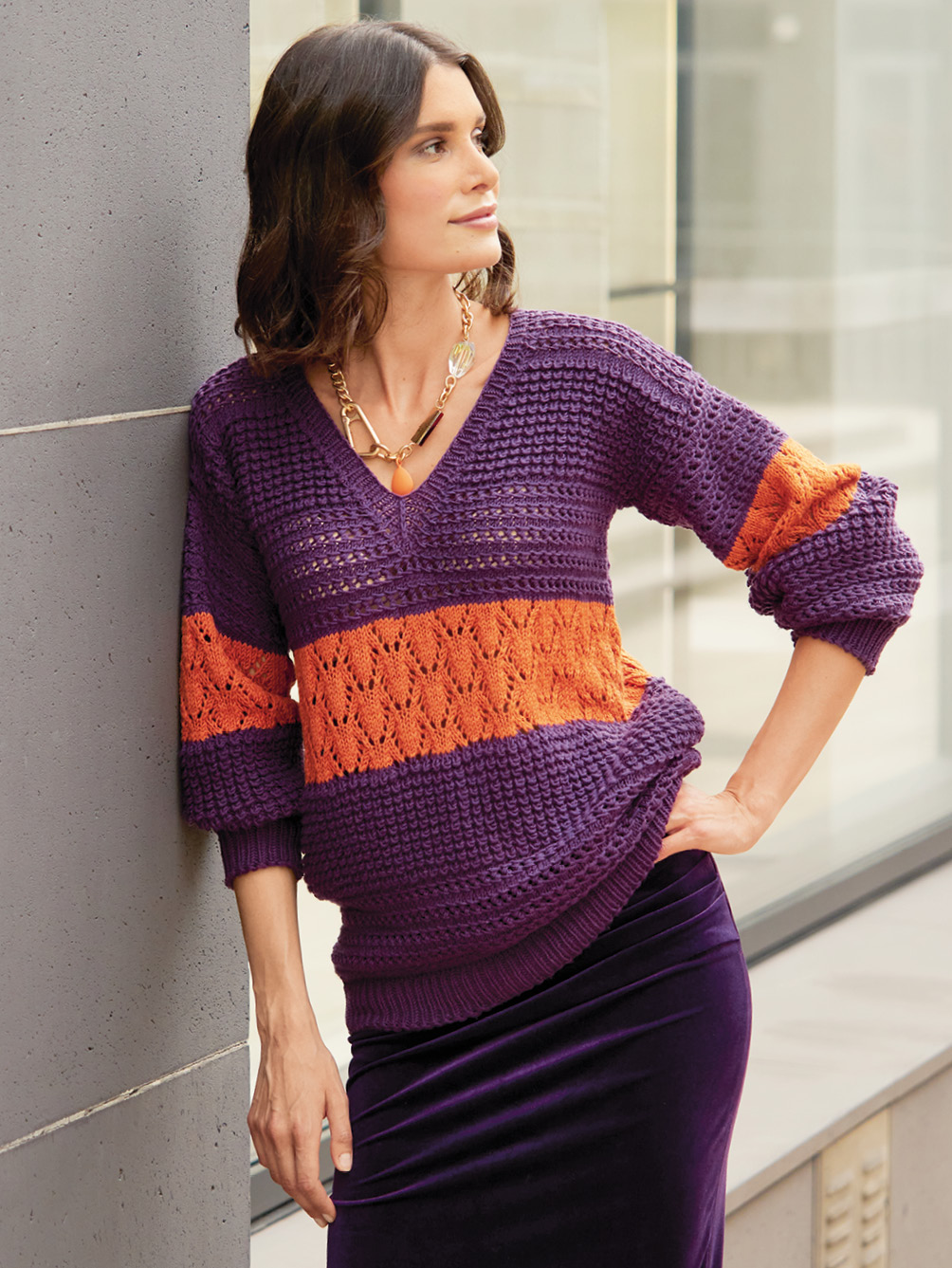 Modellansicht Bild 1: Violetter V-Ausschnittpulli mit Musterstreifen in Terracotta