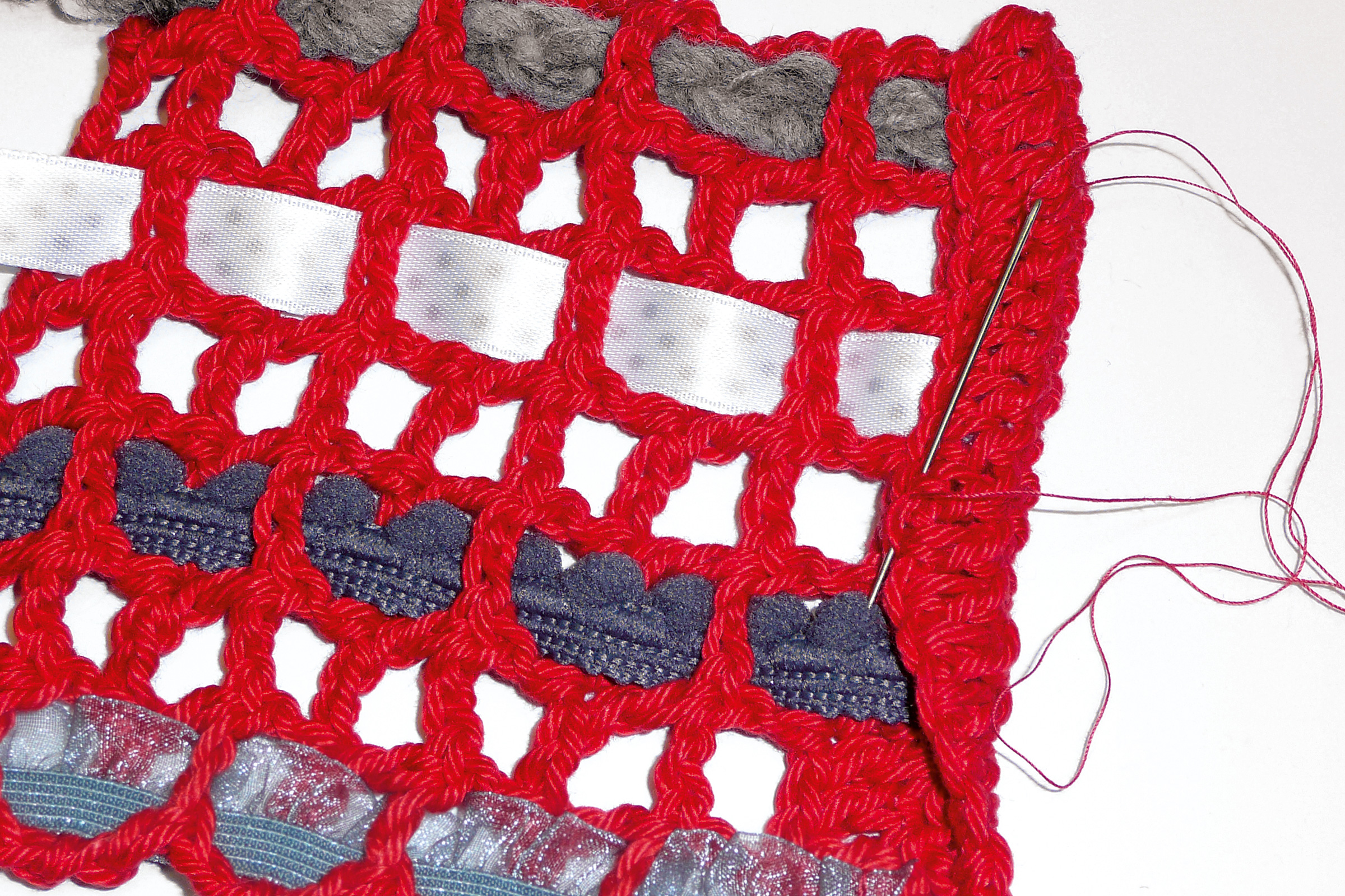 Rotes DIY Häkelgewebe mit mehrfachen Stoffeinlagen und lebhaften Mustern. Handarbeit, kreativ und einzigartig.