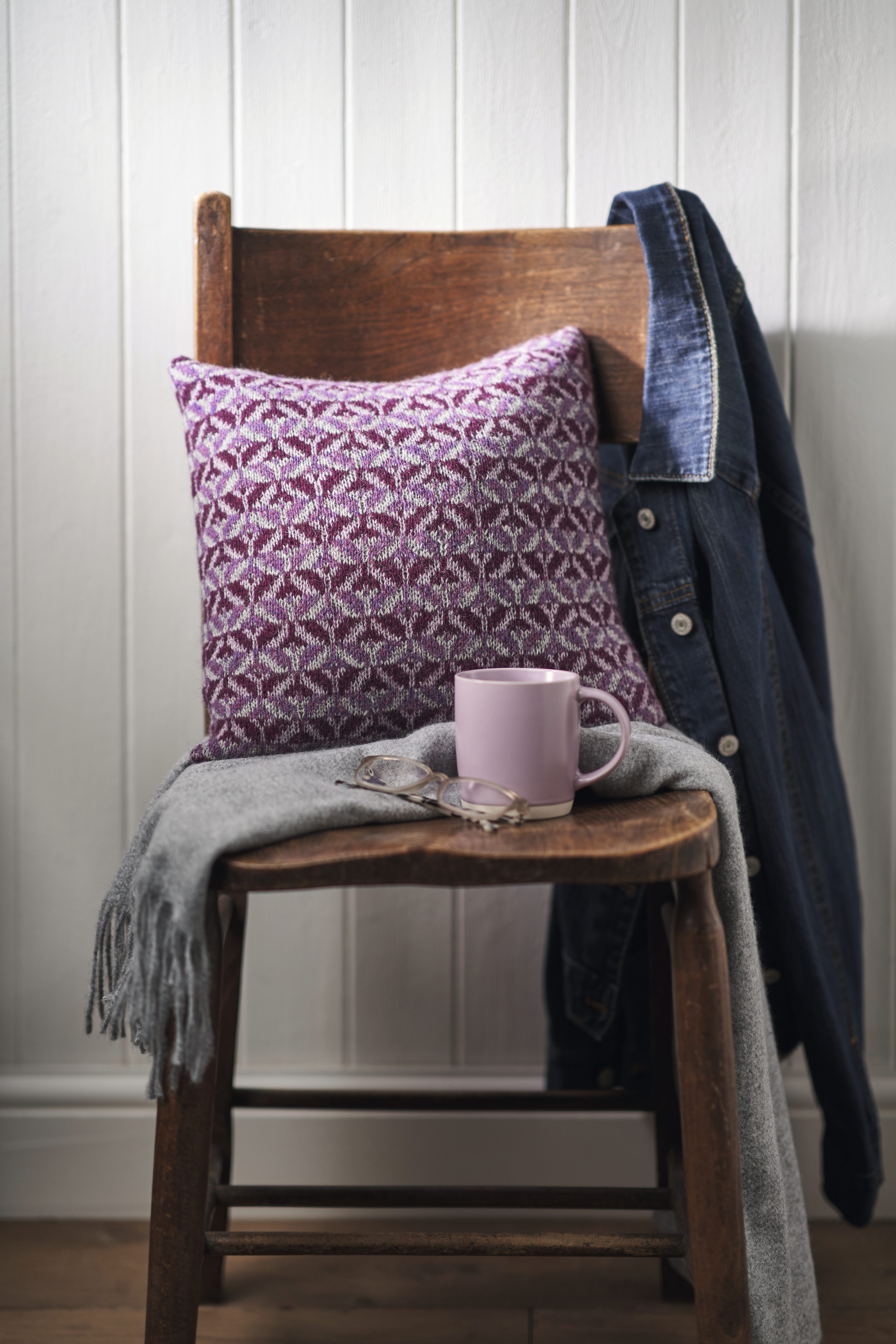 Lila Kissen mit geometrischem Muster, grauer Schal, DIY-Look, modisch und handgemacht.