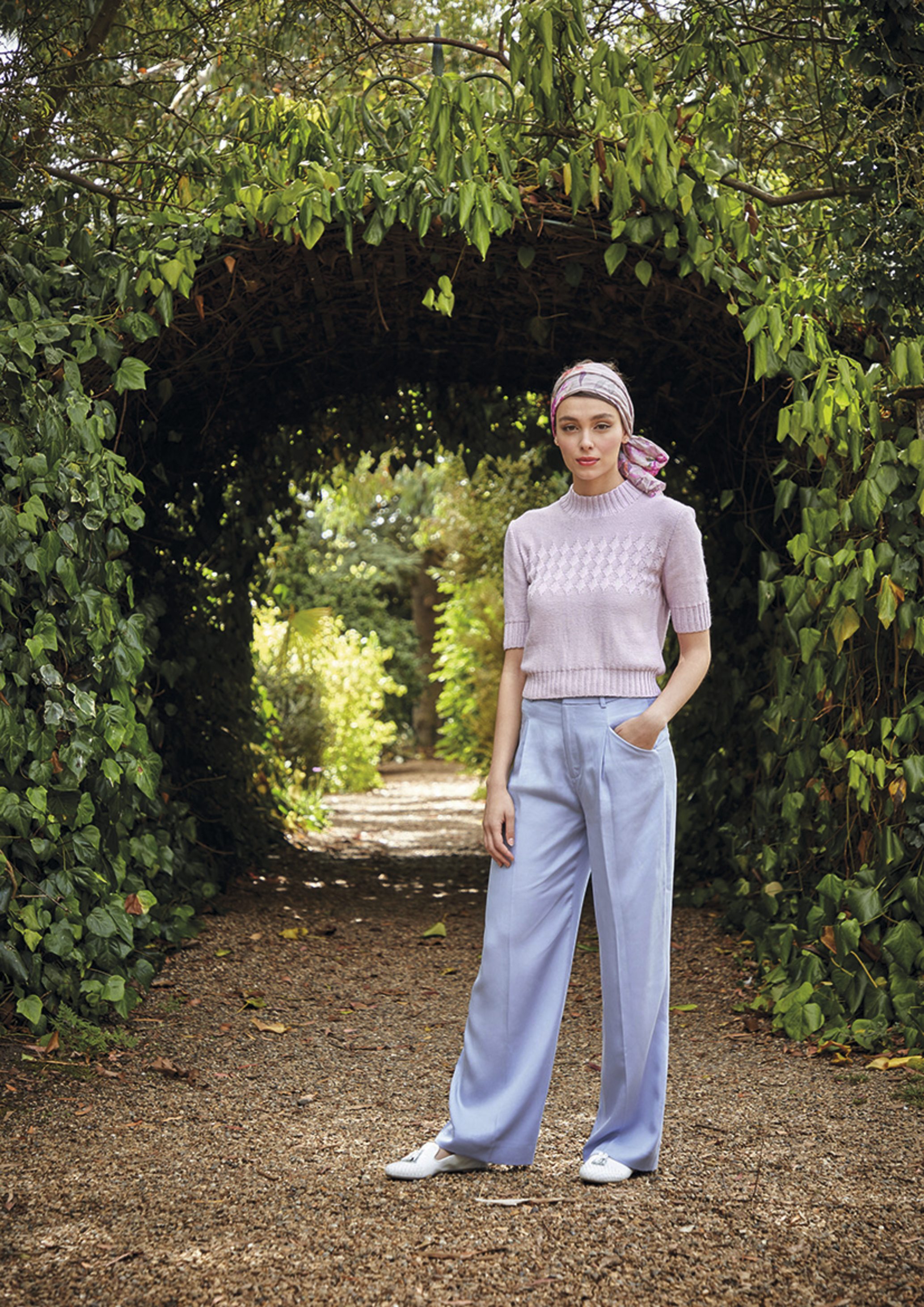 Modischer, gestrickter Kurzarm-Pullover in Flieder, kombiniert mit weit geschnittener, blauer Hose. Elegant und handgemacht.