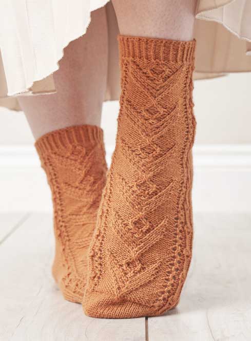 Modische, handgestrickte Socken in orange mit Zopfmuster-Design. Gemütlich und stilvoll.