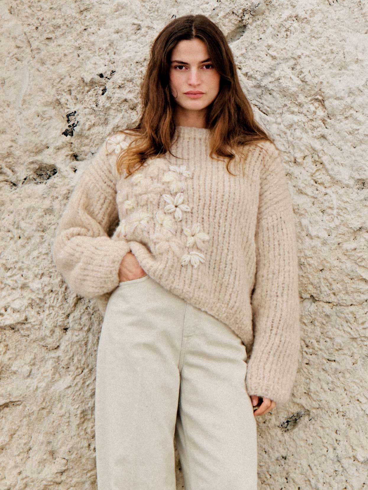 Beiger, grob gestrickter Pullover mit floralen Applikationen. Weite Ärmel, modisch und handgemacht.