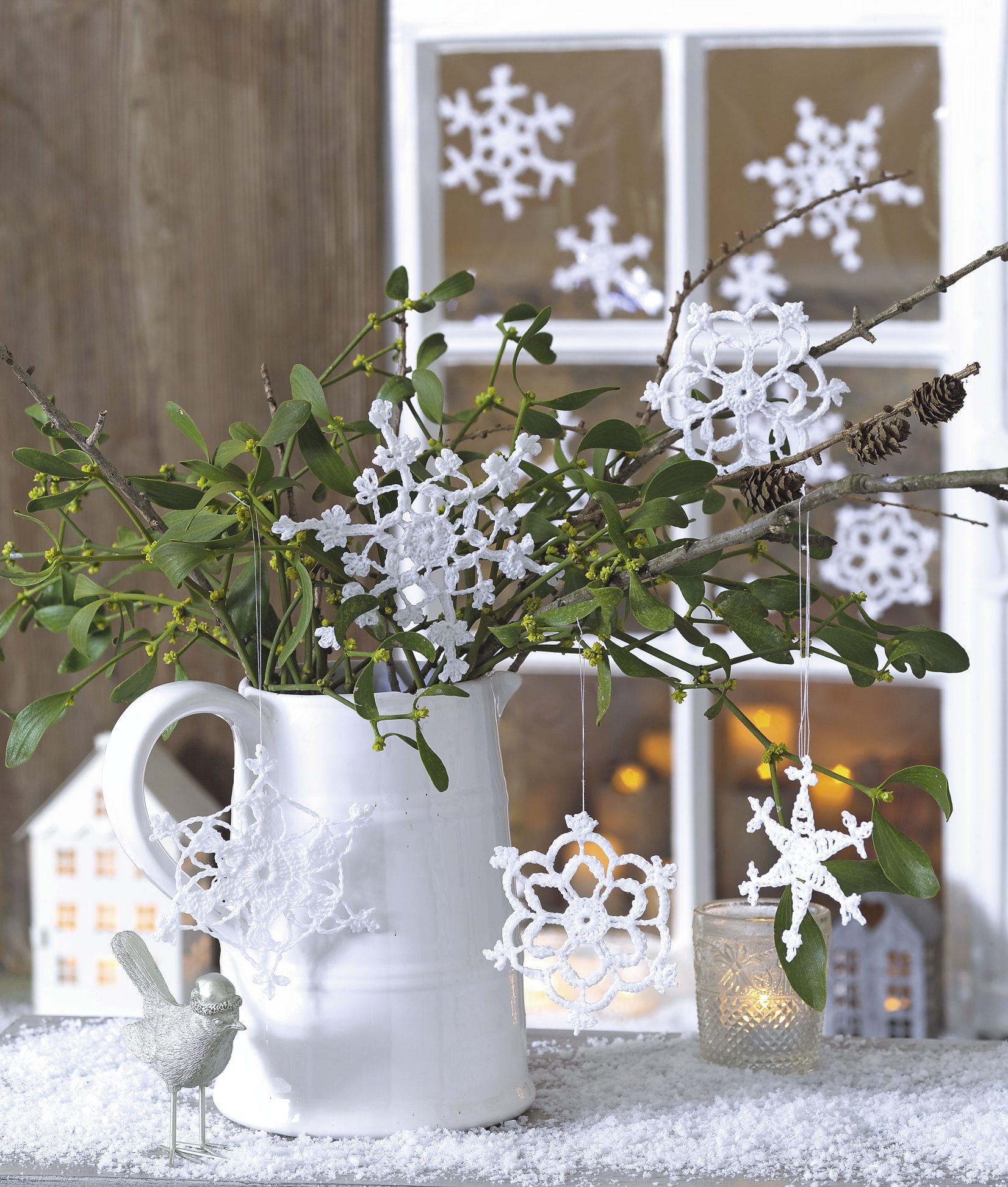 Weiße, handgemachte Schneeflocken aus Spitze schmücken Zweige. Modisch & kunstvoll im DIY-Stil.