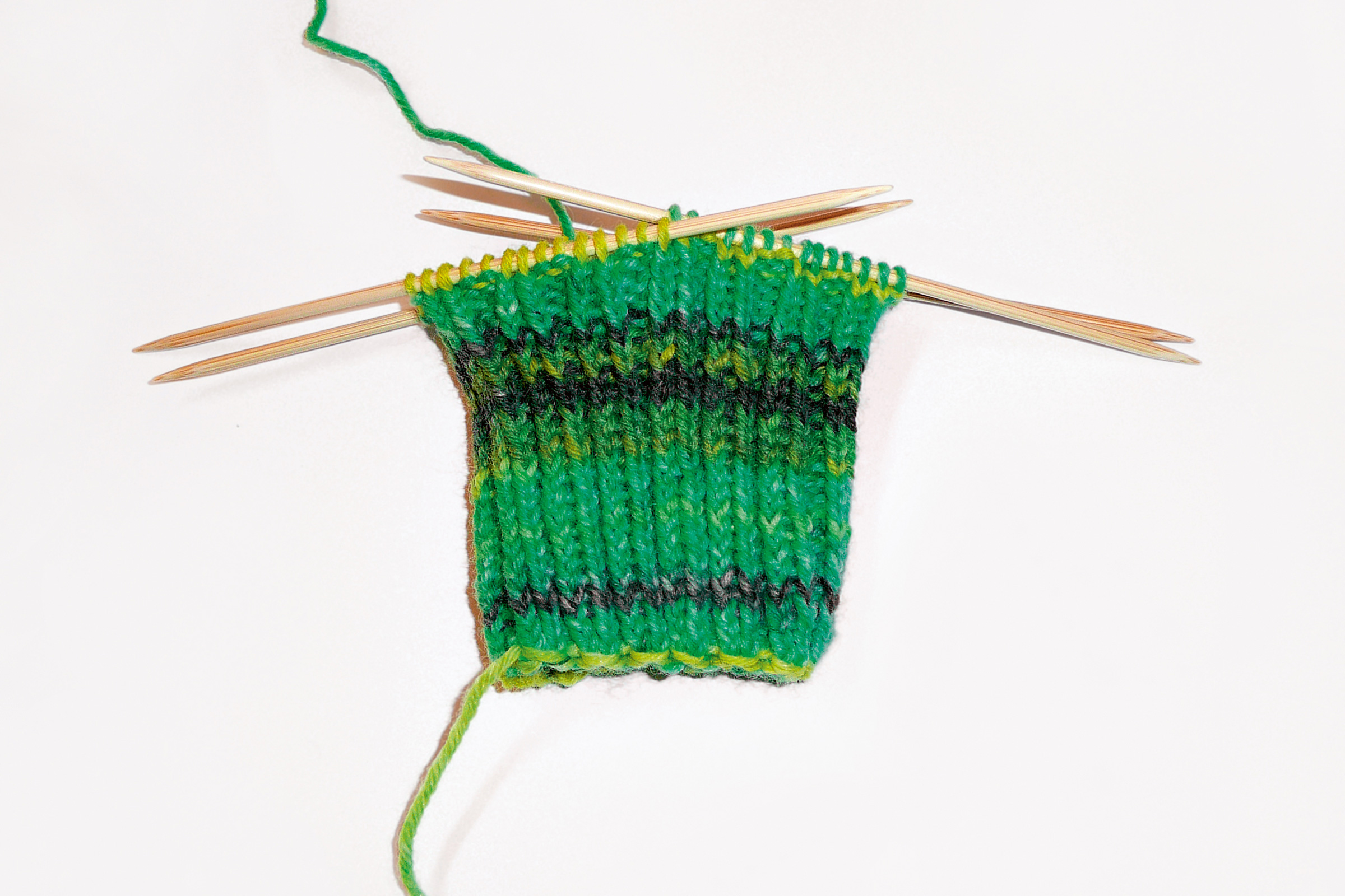Grün-gelbes Strickmuster, gestreift. DIY, modisch, elastisch, mit Nadelspiel bearbeitet.