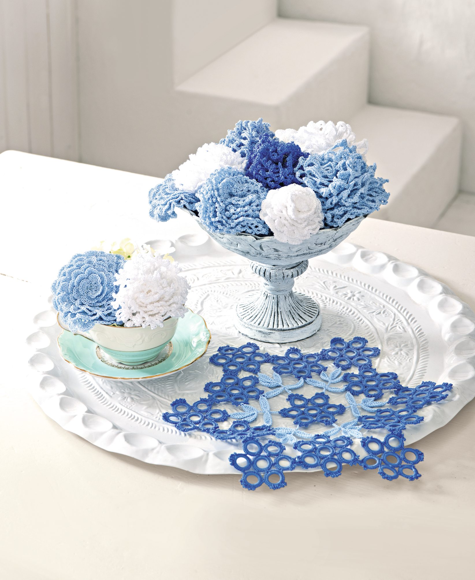Kunstvoll gehäkelte Blumen in Blau und Weiß, modisch dekorativ. Verspielt und handgemacht, ein Highlight auf dem Tisch.