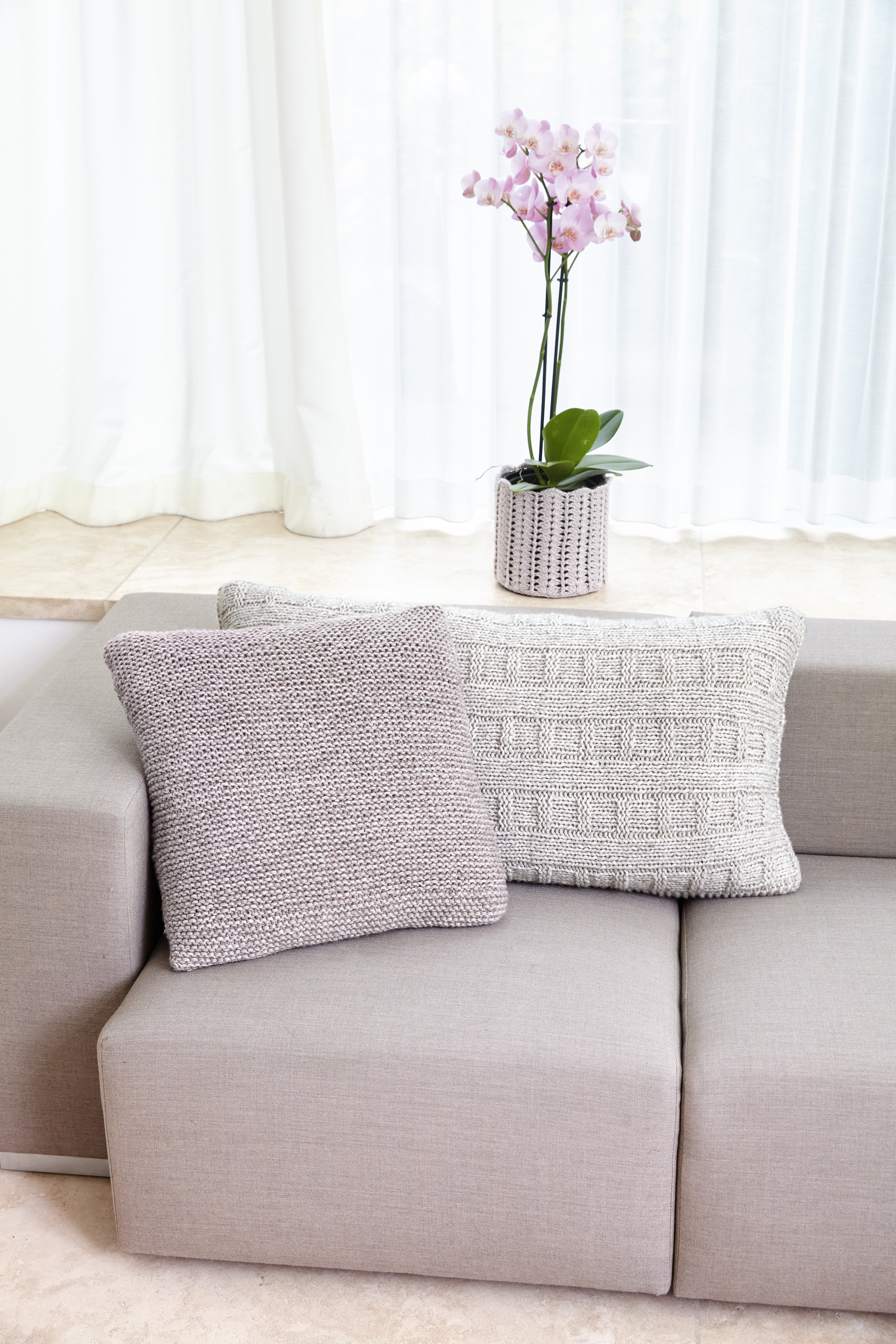 Zwei graue Strickkissen, eins grobmaschig, das andere in schickem Muster. Modern und handgemacht.