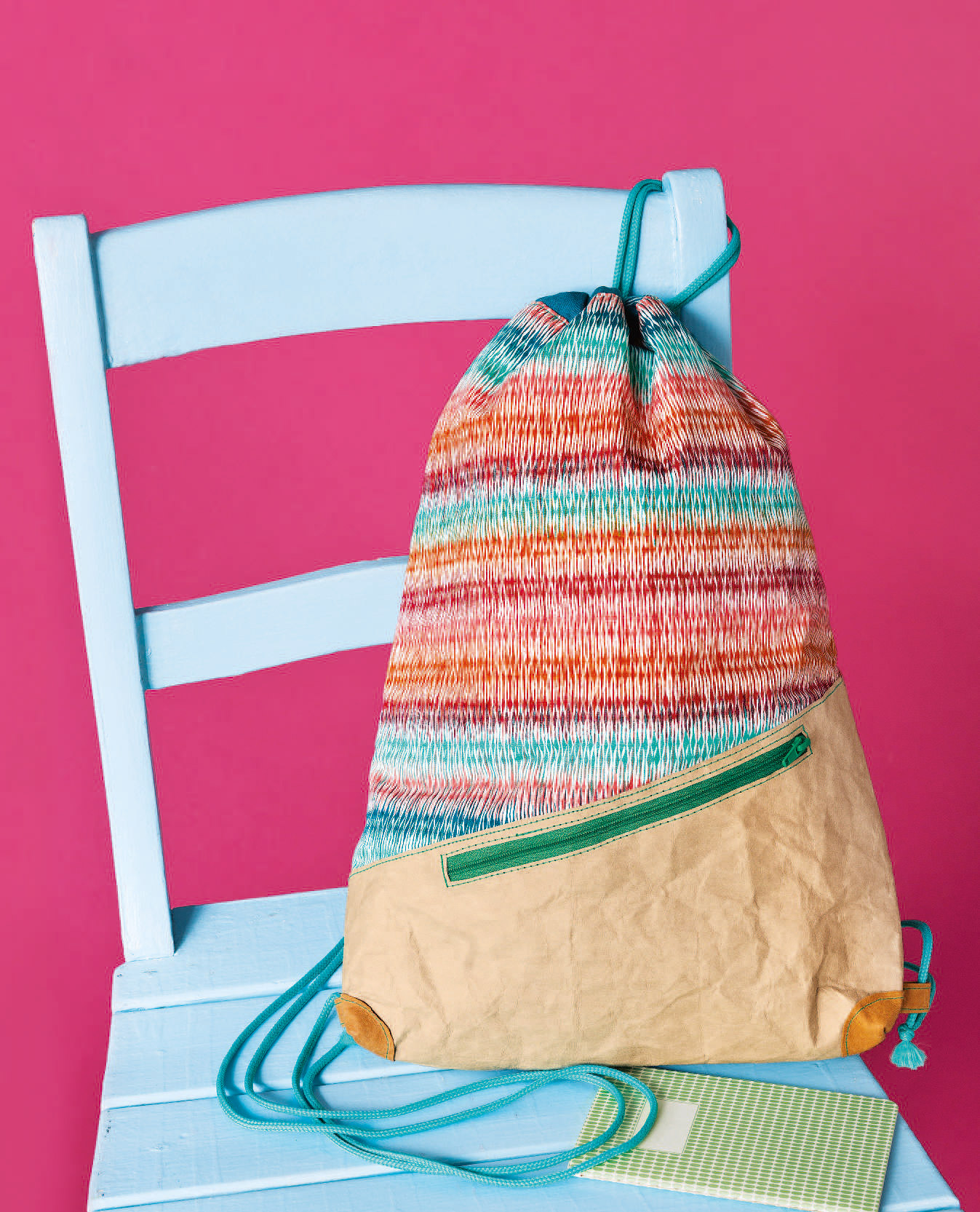 Modischer, handgemachter Rucksack mit bunten Streifen und beigem Boden. Grünem Reißverschlussakzent.