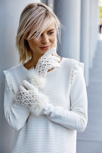 Weiße, gerippte Bluse mit Rüschen, handgestrickte Spitzenhandschuhe mit Fellbesatz; modisch, wintertauglich.